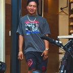 Man wearing a graphic t-shirt and shorts with a motorcycle in the background