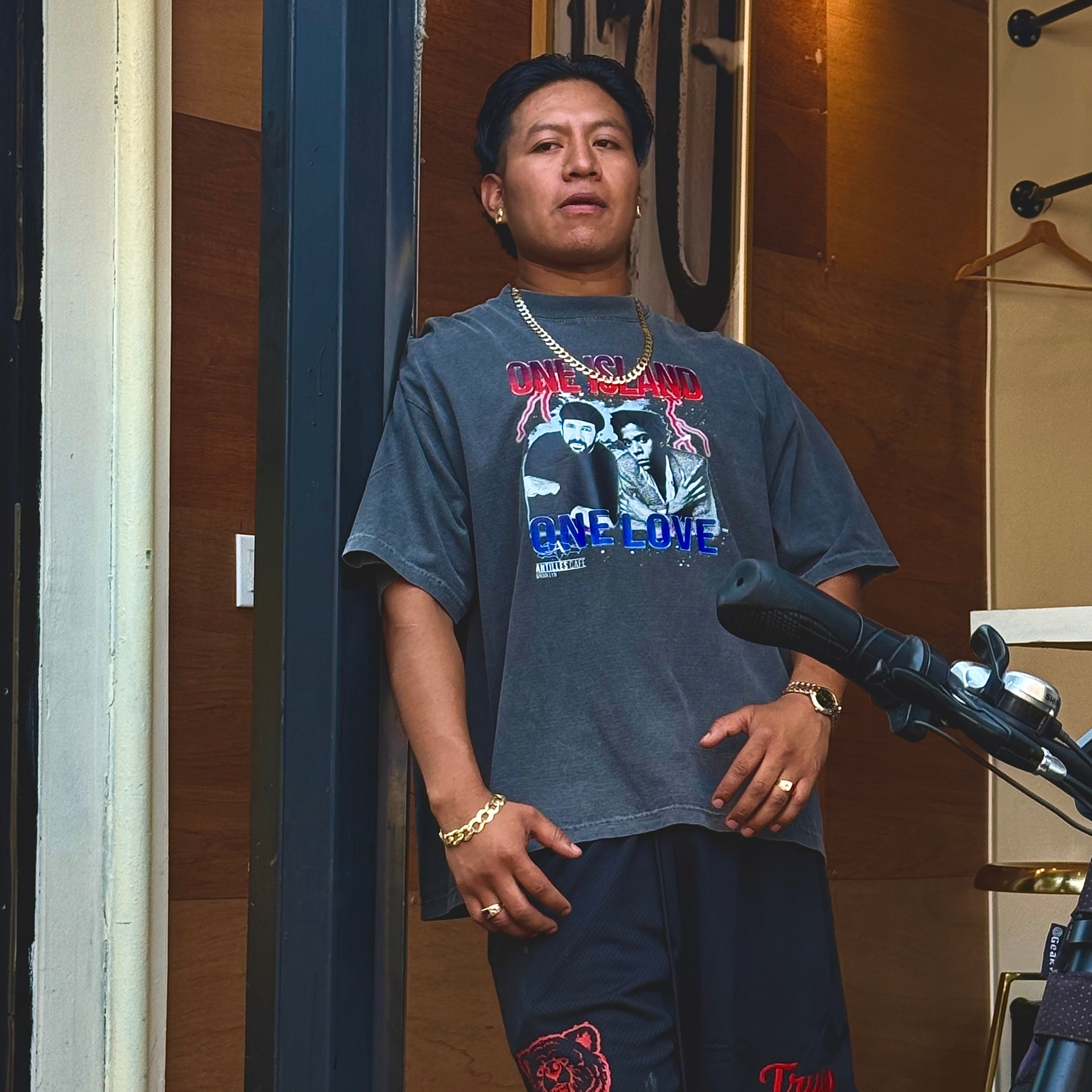 Person wearing a graphic t-shirt with text and images, standing in front of a microphone.